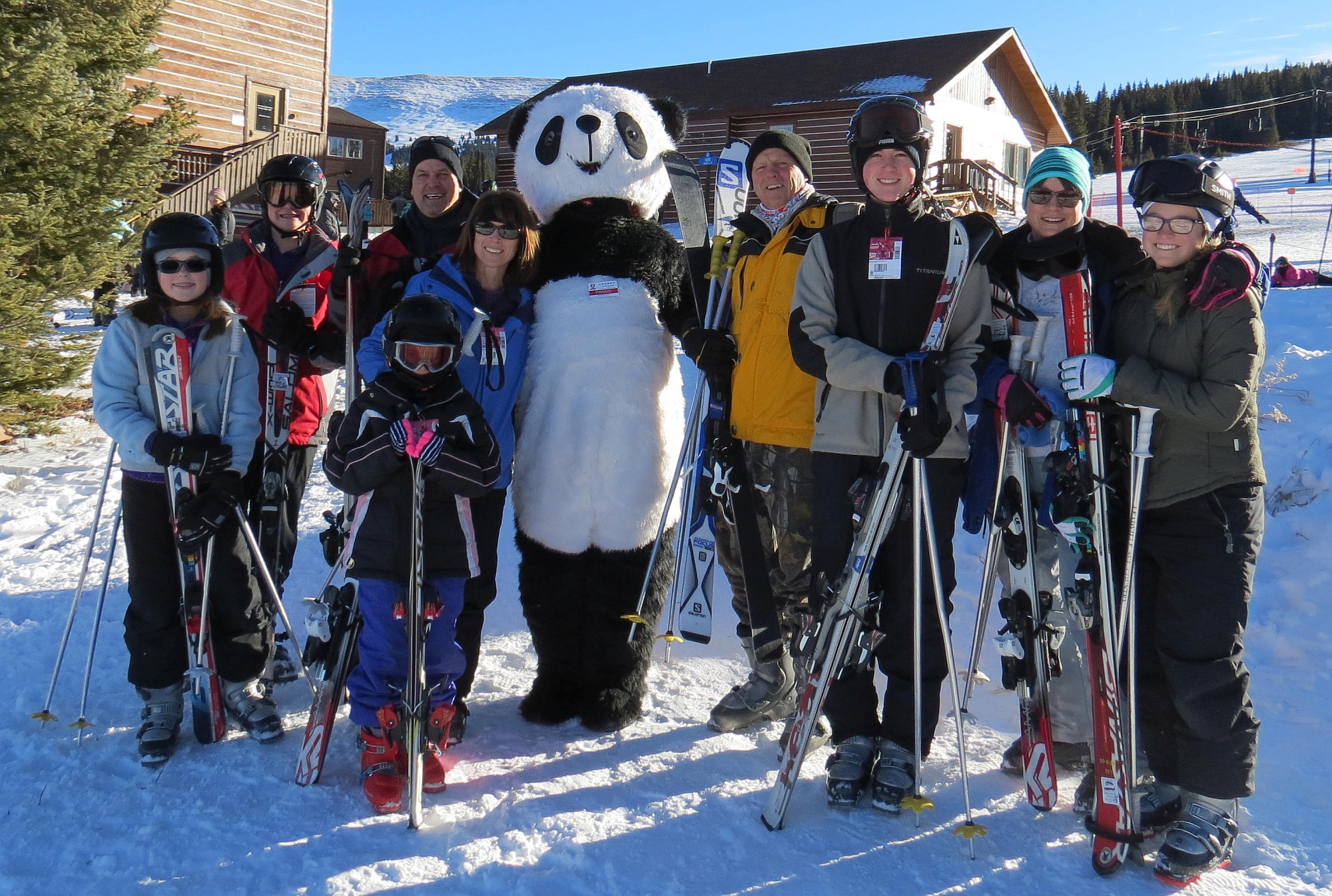 family of skiers posing with panda mascot