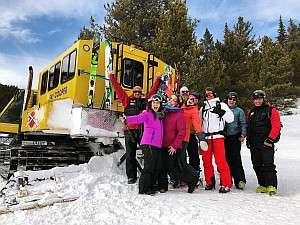 skiers standing beside a snowcat