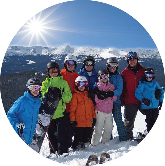 smiling group with sun and mountain peaks in background