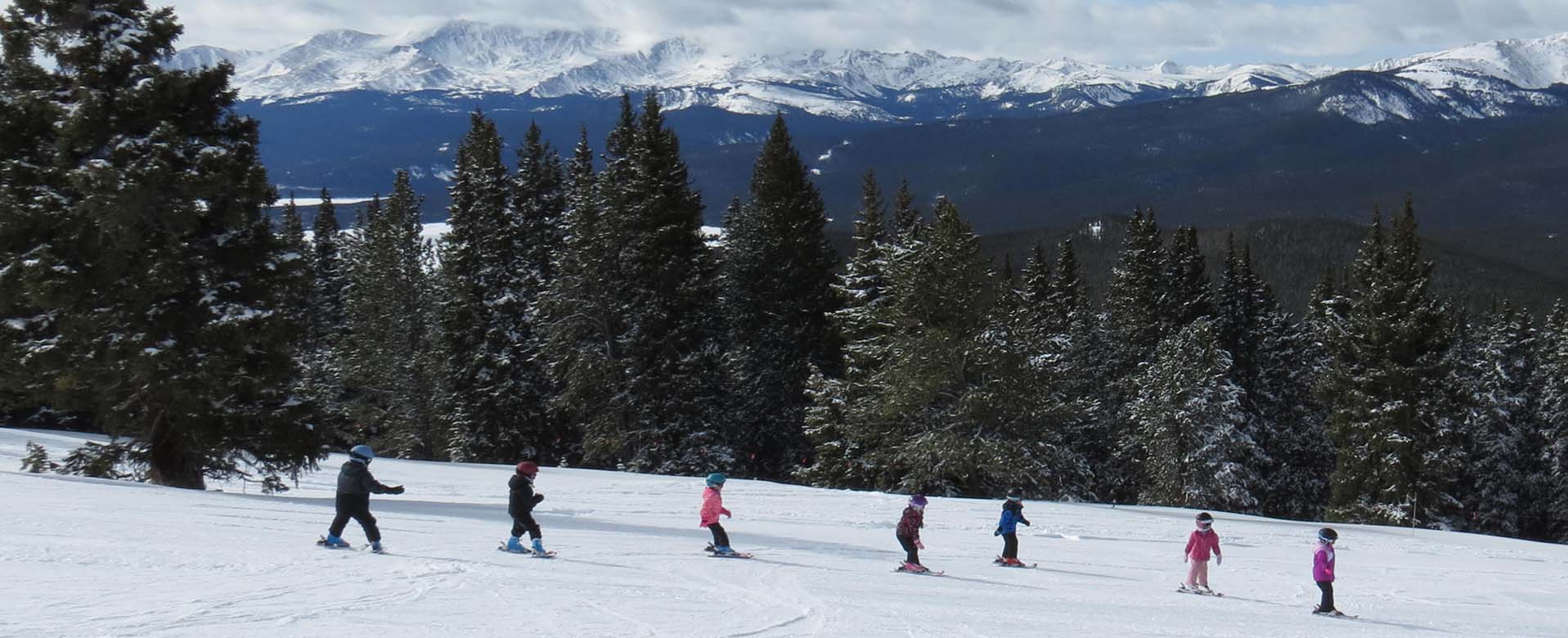 young skiers skiing down the slopes in a line