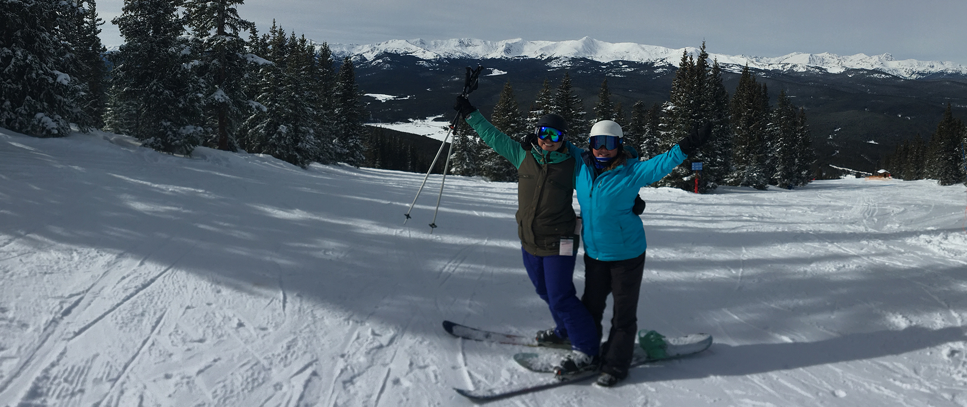 2 people posing on the top of a ski trail